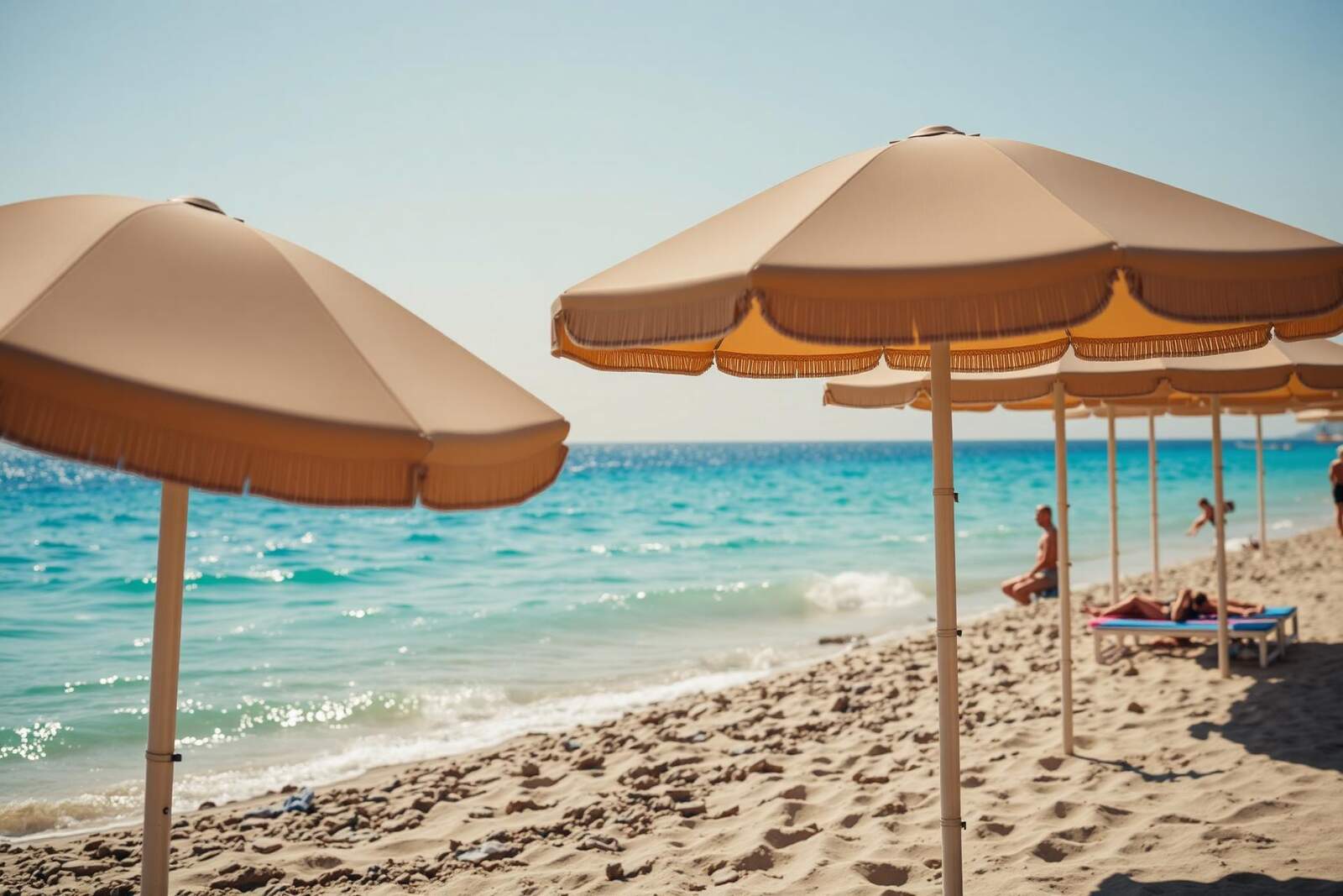 Sonnenschirme an einem Sandstrand mit türkisem Meer im warmen Frühsommerlicht