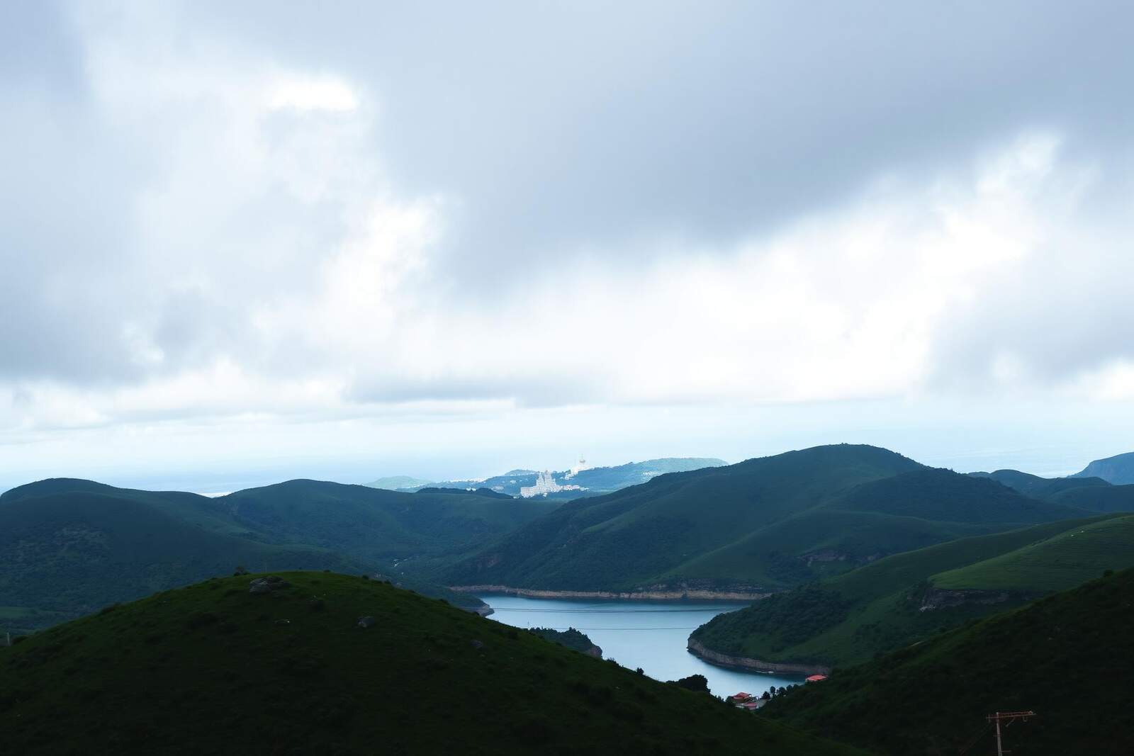 Grüne Hügellandschaft mit Bucht und Wolkenhimmel im weichen Winterlicht