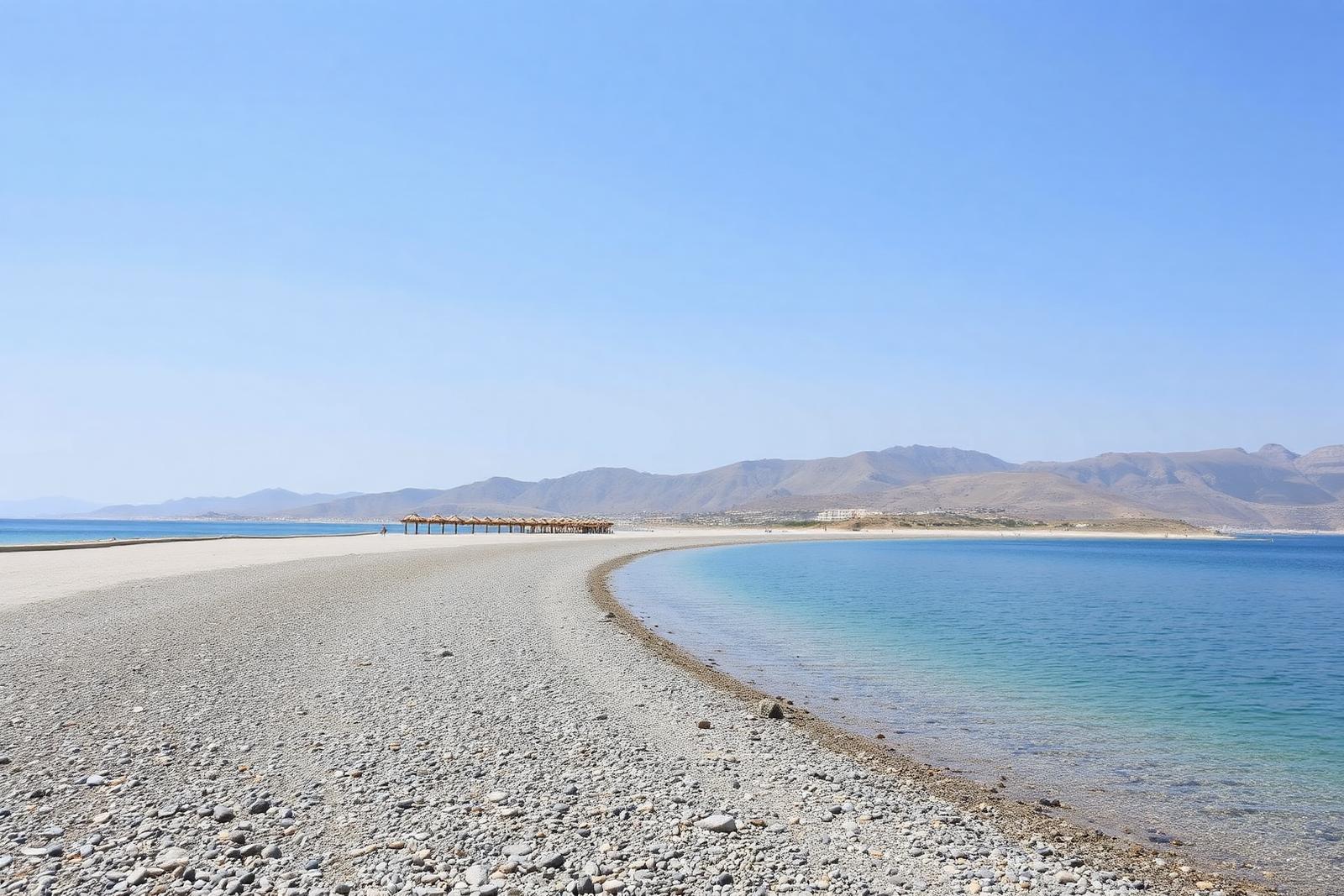 Weiter Kiesstrand von Afandou mit ruhigem Wasser und Bergen im Hintergrund