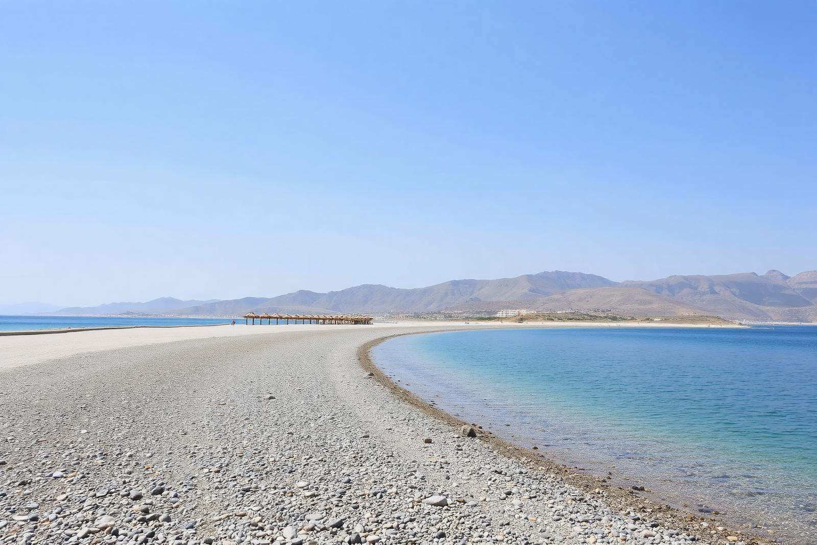 Weiter Kiesstrand von Afandou mit ruhigem Wasser und Bergen im Hintergrund